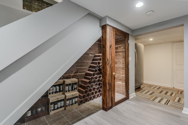 wine room featuring baseboards, a drop ceiling, wood finished floors, and recessed lighting