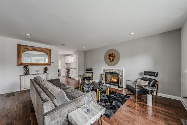 living room with visible vents, baseboards, a tiled fireplace, wood-type flooring, and recessed lighting