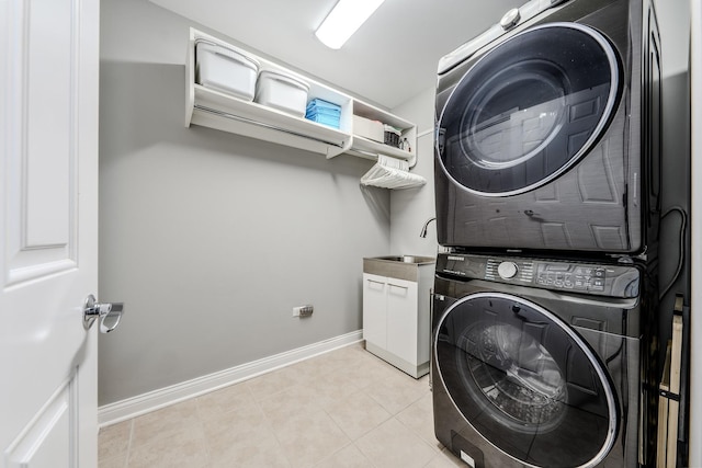 laundry room with light tile patterned floors, a sink, baseboards, stacked washer / drying machine, and cabinet space