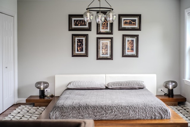 bedroom featuring a notable chandelier, baseboards, and wood finished floors