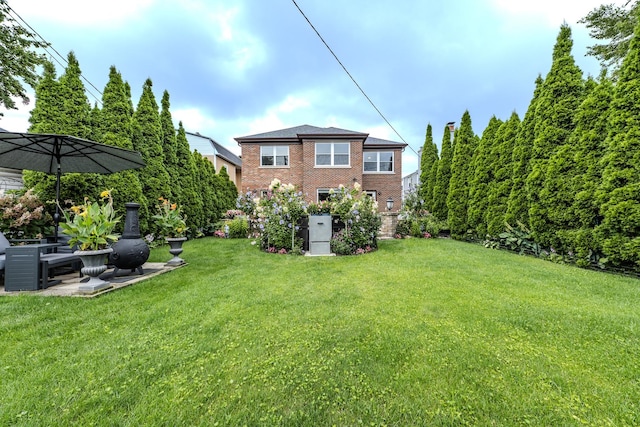 rear view of property featuring a patio area, brick siding, and a yard