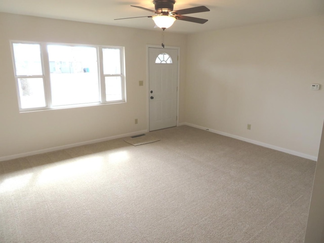 empty room featuring baseboards, a ceiling fan, and light colored carpet