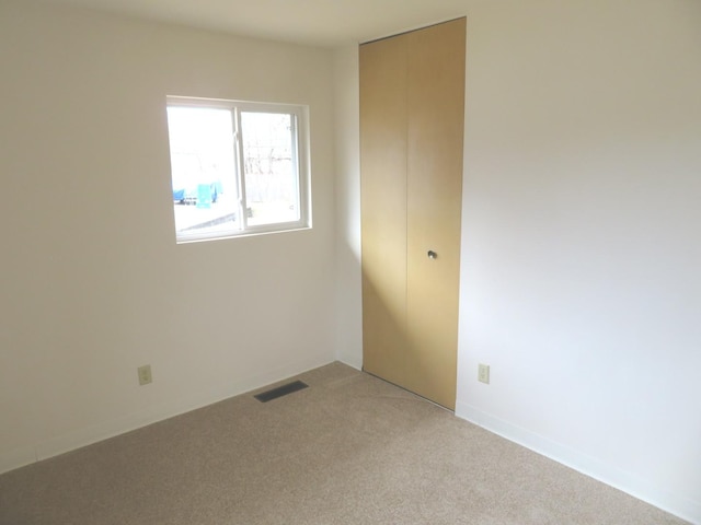 spare room featuring visible vents and light colored carpet