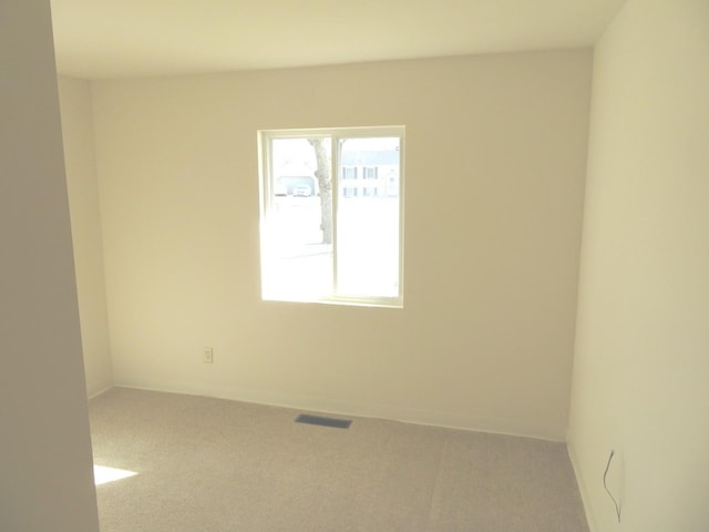 unfurnished room featuring carpet floors, visible vents, and baseboards