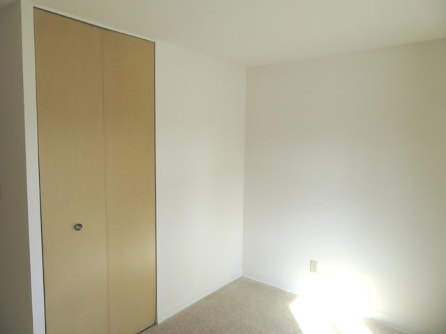 unfurnished bedroom with a closet and light colored carpet