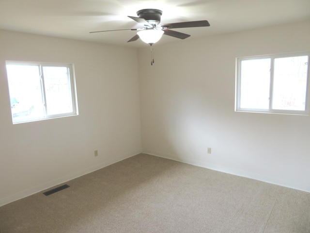 unfurnished room featuring baseboards, visible vents, a ceiling fan, and light colored carpet