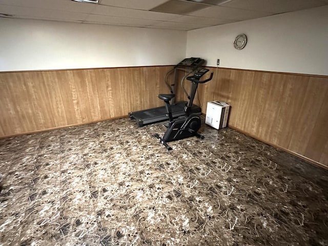 workout area with a wainscoted wall, wood walls, and a paneled ceiling