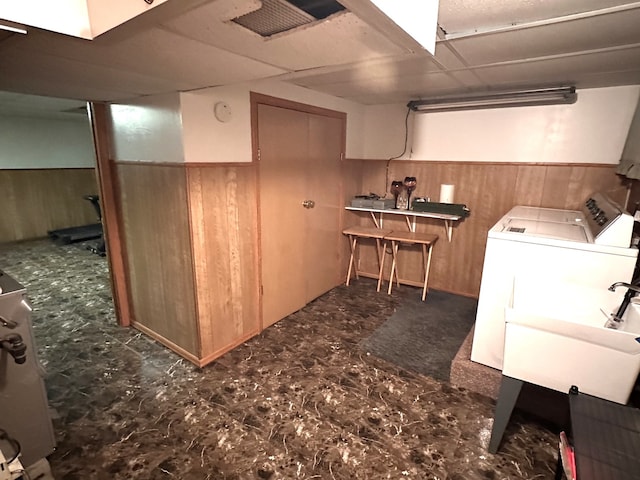 interior space with a wainscoted wall, a sink, washing machine and clothes dryer, and wooden walls