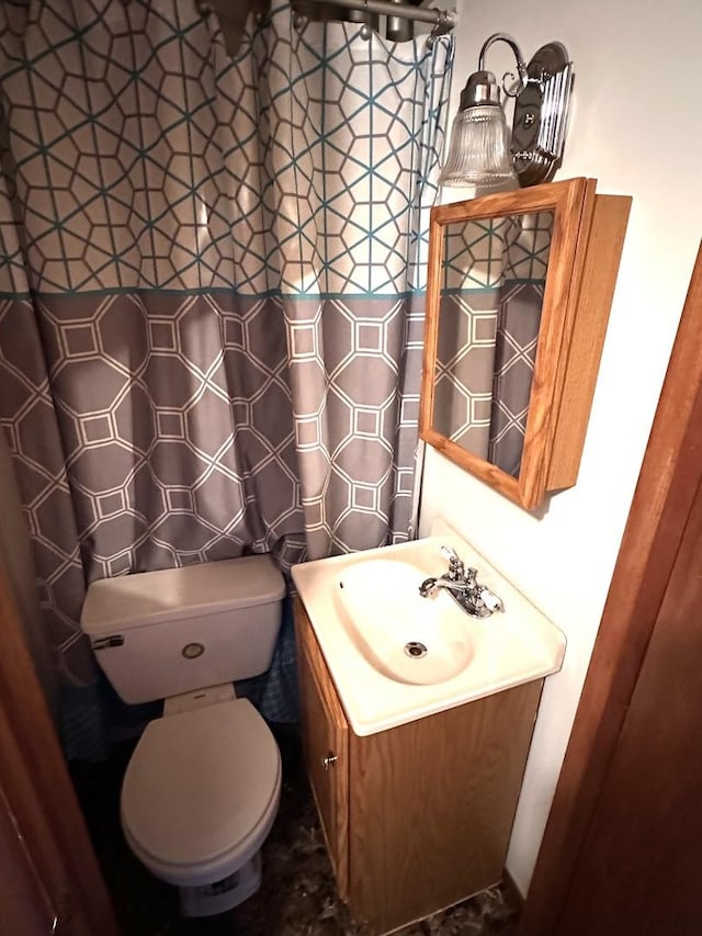 full bath featuring toilet, a shower with shower curtain, and vanity