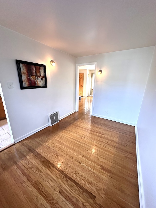 spare room with light wood-style floors, visible vents, and baseboards