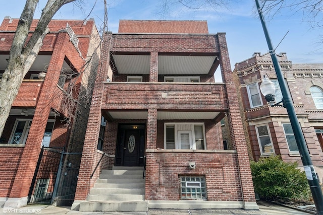 view of front of home featuring brick siding and a balcony