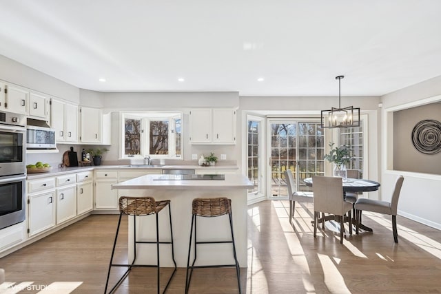 kitchen with wood finished floors, appliances with stainless steel finishes, a sink, and a wealth of natural light