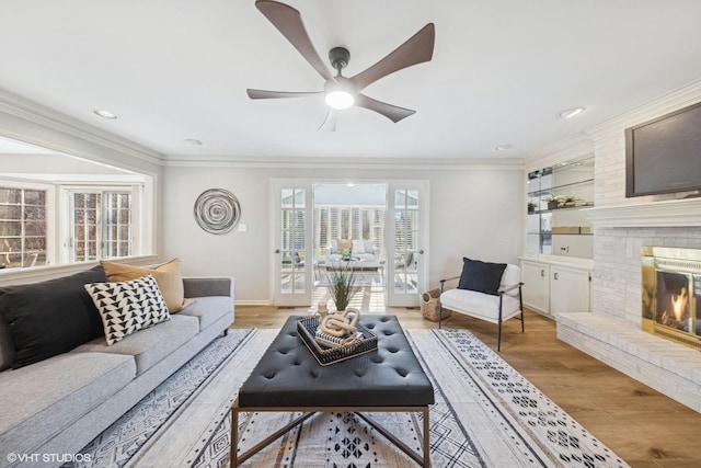 living room featuring baseboards, light wood-style floors, a fireplace, and crown molding