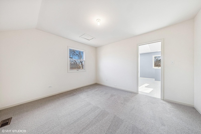 carpeted empty room featuring baseboards and vaulted ceiling