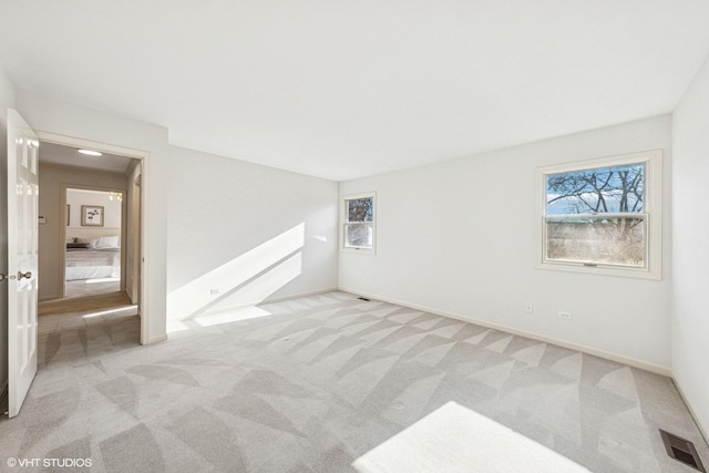 spare room featuring carpet, visible vents, and baseboards