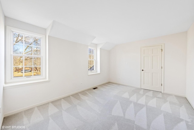 additional living space with carpet floors, lofted ceiling, visible vents, and baseboards