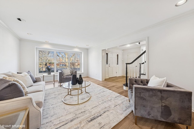 living room featuring light wood-type flooring, crown molding, stairway, and baseboards