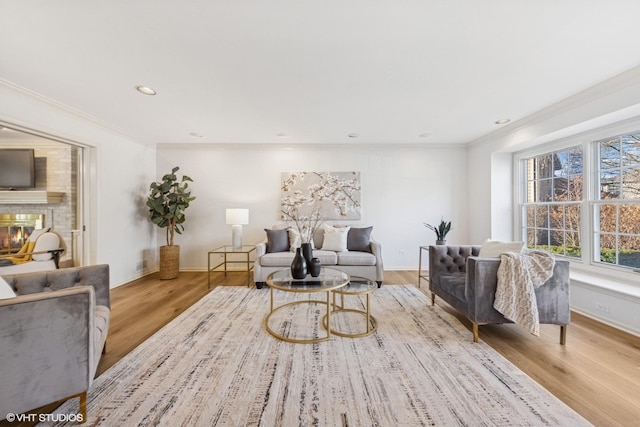 living area featuring ornamental molding, a brick fireplace, baseboards, and wood finished floors