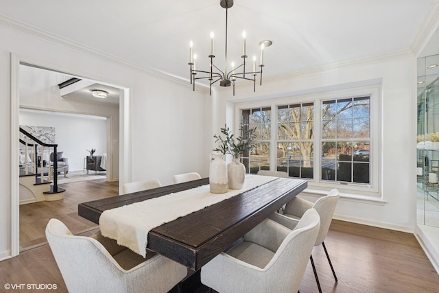 dining area with a notable chandelier, crown molding, wood finished floors, baseboards, and stairs