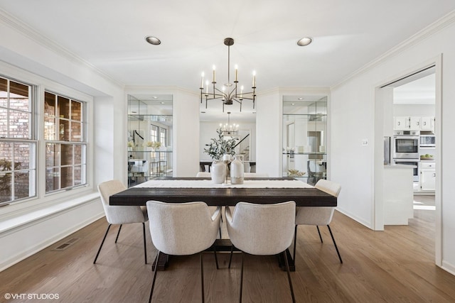 dining area with crown molding, a notable chandelier, visible vents, wood finished floors, and baseboards