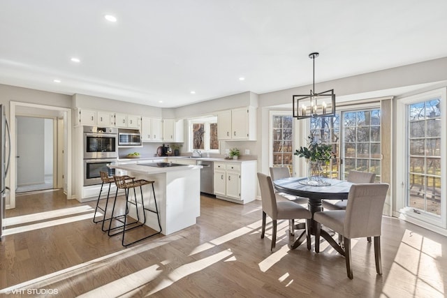 kitchen with white cabinetry, light countertops, appliances with stainless steel finishes, light wood-type flooring, and a center island