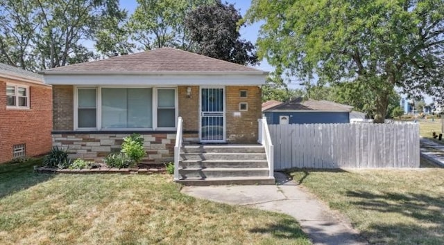 bungalow with a front yard, stone siding, and fence