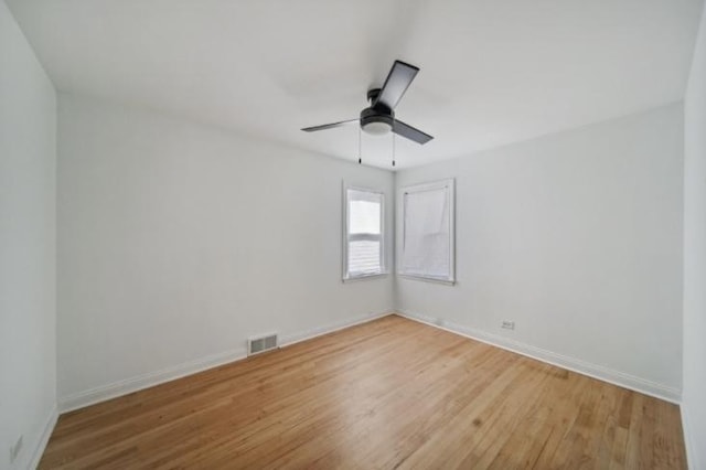 empty room with light wood-style floors, visible vents, baseboards, and a ceiling fan