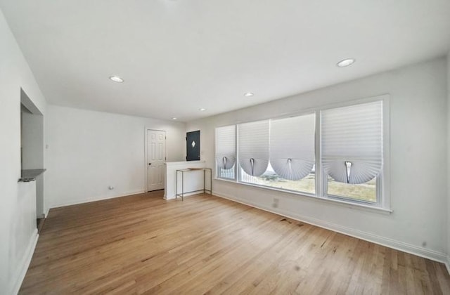 empty room with light wood finished floors, baseboards, and recessed lighting