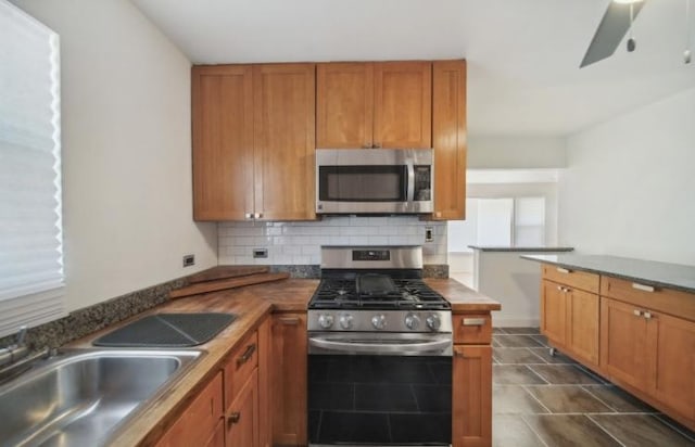kitchen with brown cabinets, backsplash, stainless steel appliances, and a sink