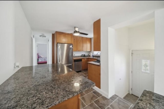 kitchen featuring ceiling fan, brown cabinets, a peninsula, stainless steel appliances, and a sink