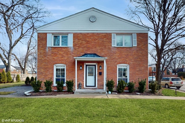 view of front of home featuring brick siding, a front yard, and fence