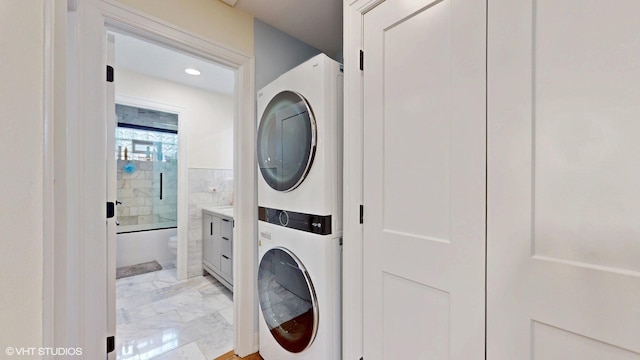 clothes washing area featuring laundry area, marble finish floor, and stacked washing maching and dryer