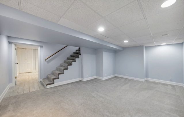 finished basement with a drop ceiling, recessed lighting, carpet flooring, baseboards, and stairs