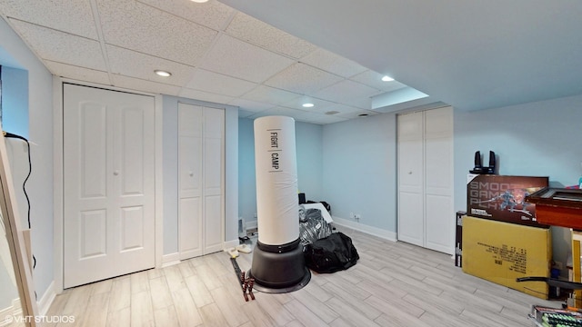 interior space with a paneled ceiling, light wood-style floors, and baseboards