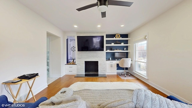 living area with a fireplace, baseboards, wood finished floors, and recessed lighting