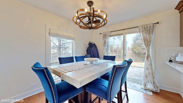 dining space with an inviting chandelier, light wood-style flooring, and baseboards