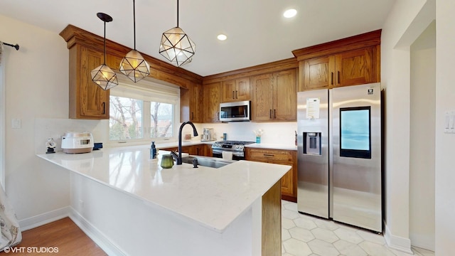 kitchen with brown cabinetry, a peninsula, stainless steel appliances, a sink, and recessed lighting