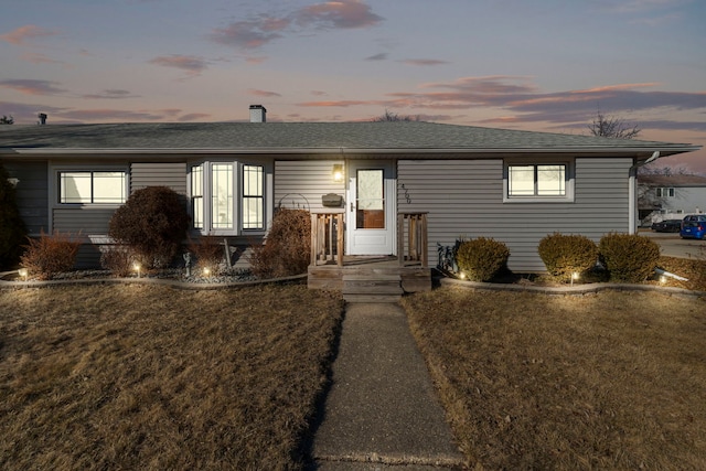 view of front of property featuring a shingled roof, a chimney, and a front yard