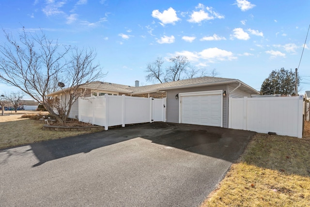 view of front facade with driveway, an attached garage, and fence