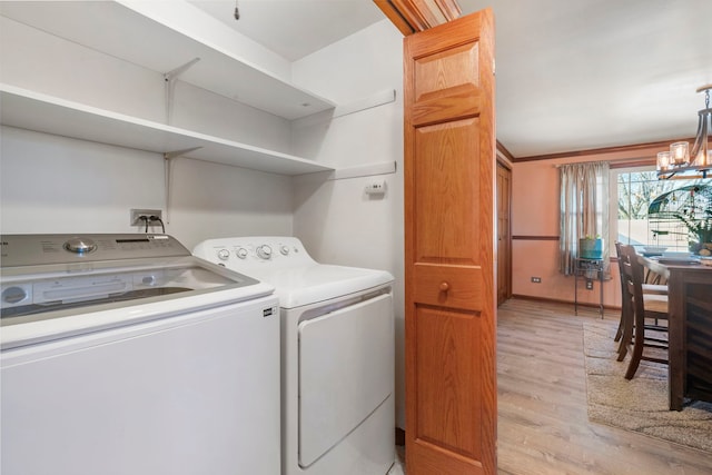 laundry room featuring laundry area, baseboards, light wood-type flooring, washing machine and clothes dryer, and an inviting chandelier