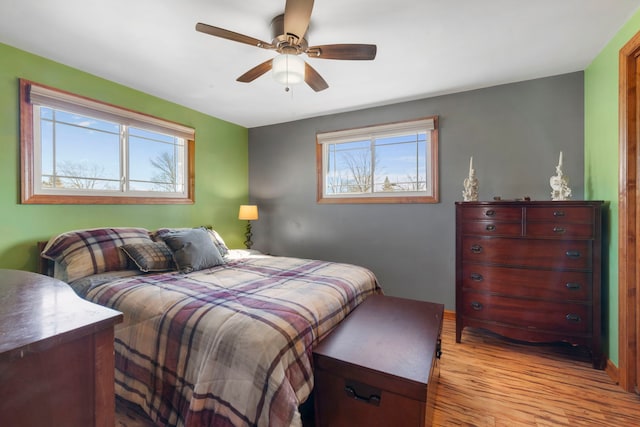 bedroom with light wood-style floors, multiple windows, and a ceiling fan