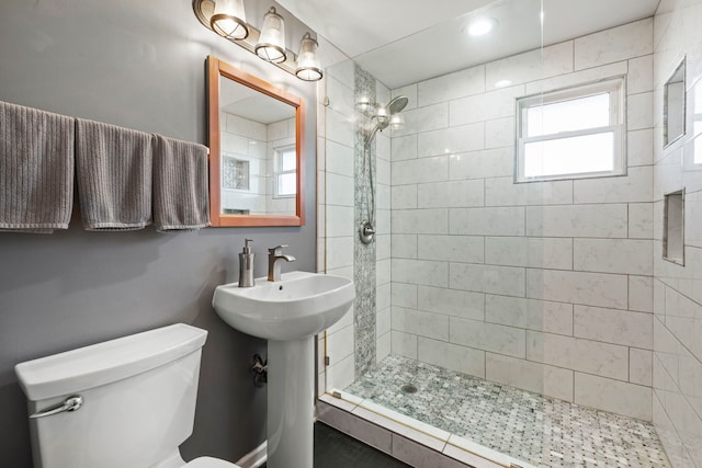 bathroom featuring tiled shower, a sink, and toilet