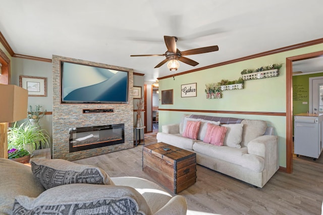 living area featuring ornamental molding, a fireplace, wood finished floors, and a ceiling fan