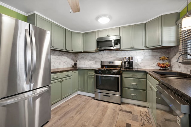 kitchen with green cabinets, stainless steel appliances, a sink, and decorative backsplash