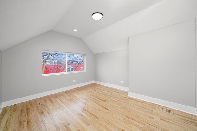 bonus room featuring baseboards, visible vents, vaulted ceiling, and wood finished floors