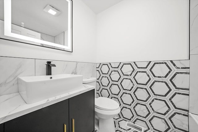 bathroom with tile walls, toilet, vanity, and wainscoting