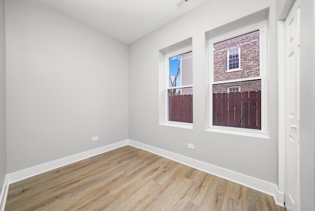 spare room featuring baseboards, visible vents, and wood finished floors