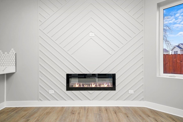interior details featuring baseboards, a glass covered fireplace, and wood finished floors