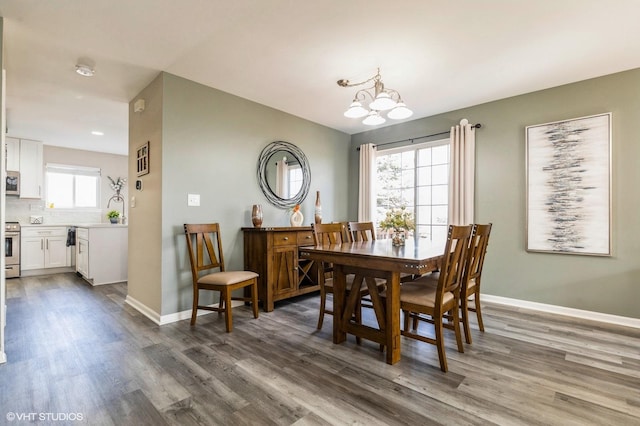 dining area with a chandelier, wood finished floors, and baseboards