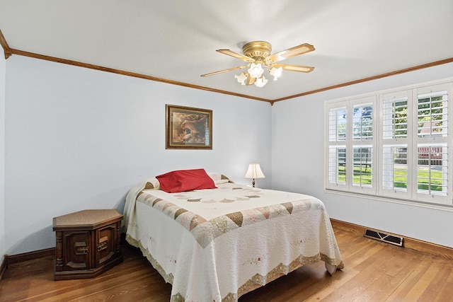 bedroom featuring ceiling fan, hardwood / wood-style flooring, visible vents, baseboards, and ornamental molding